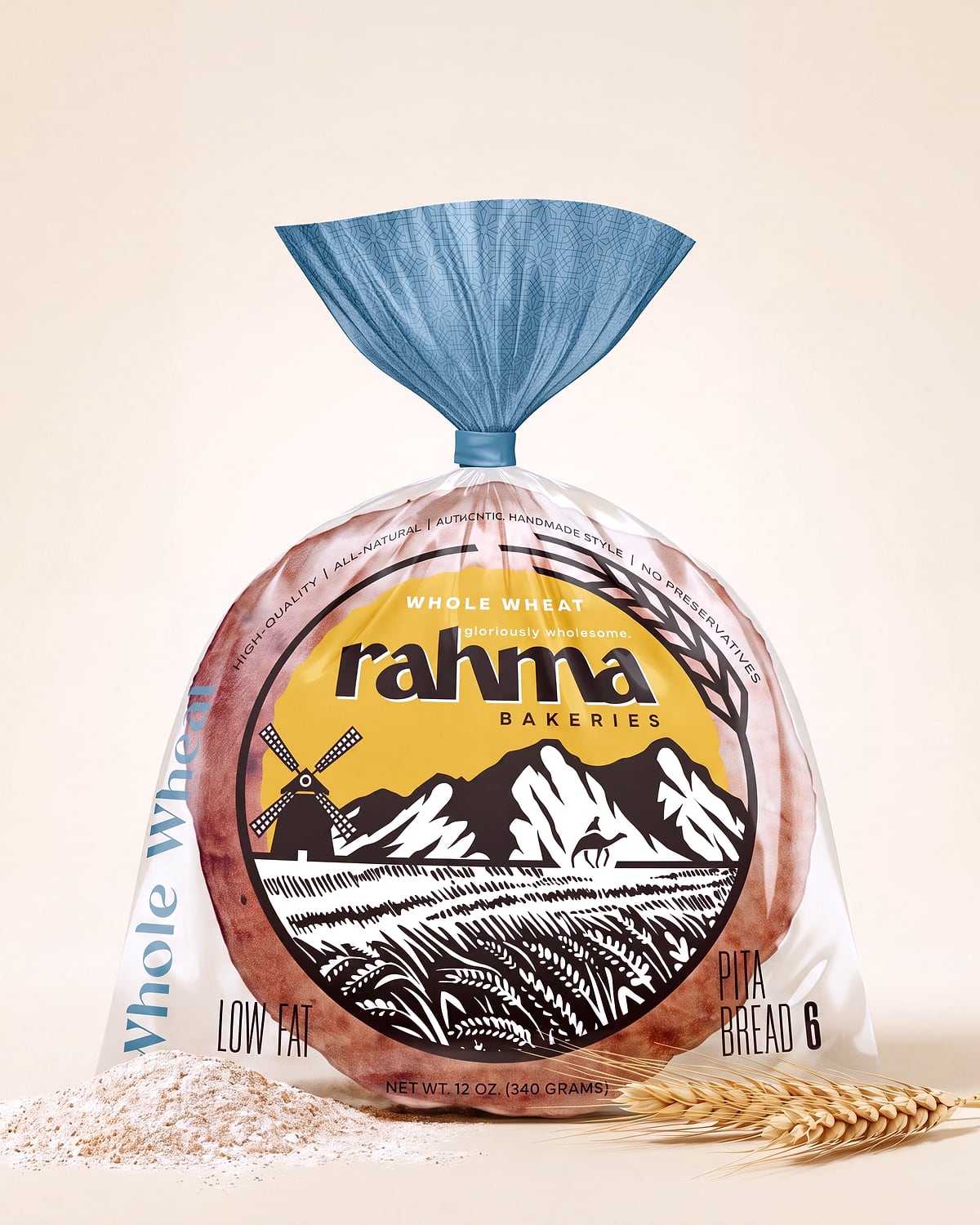 A bag of Rahma Whole Wheat Pita Bread standing on a cream studio sweep, with a small pile of flour and a wheat stalk at its base.